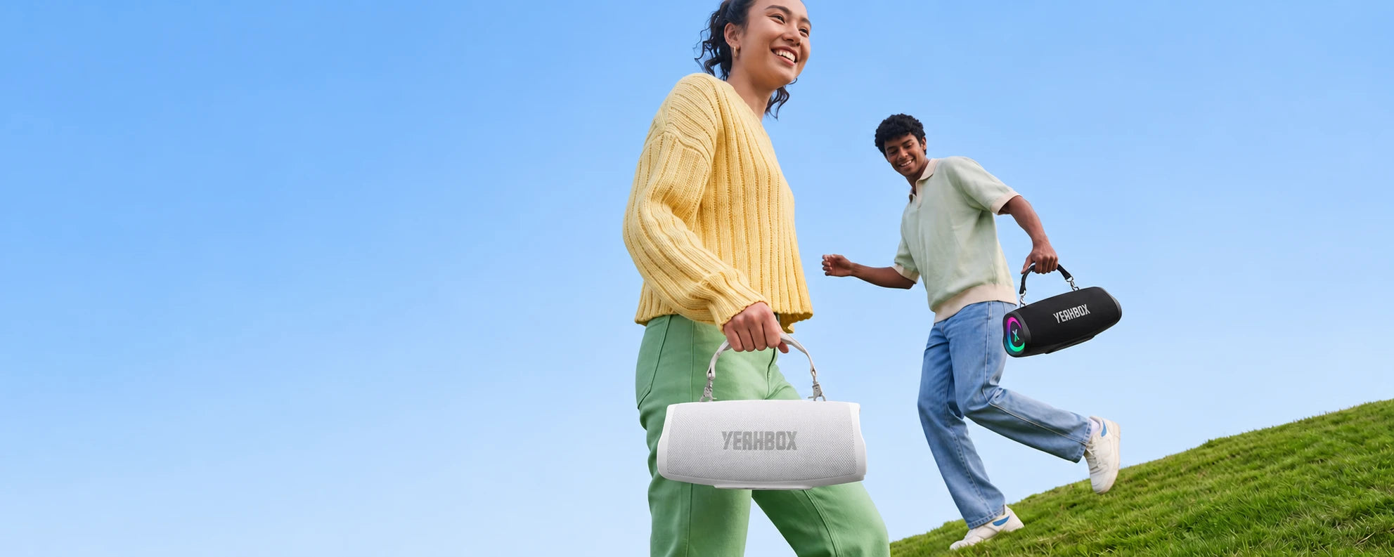 Sonic Boom POP — Two people outdoors holding white and black YEAHBOX POP speakers